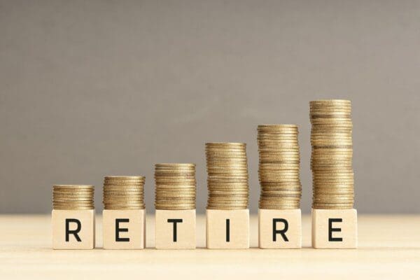 Retire spelled with wooden blocks with coins stacked represents savings retirement funds