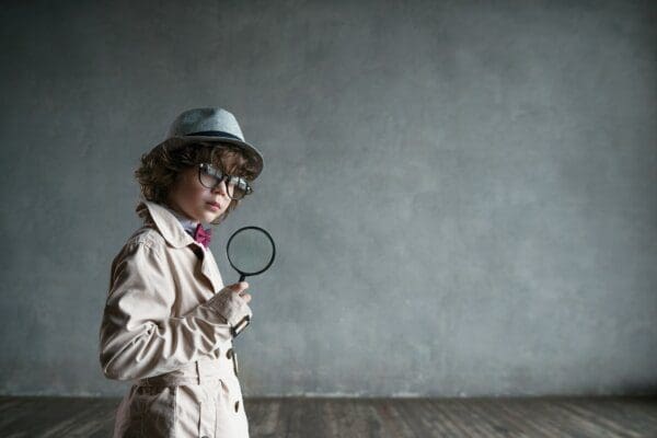Young INTP boy in a detective coat with magnifying glass mimics Sherlock 