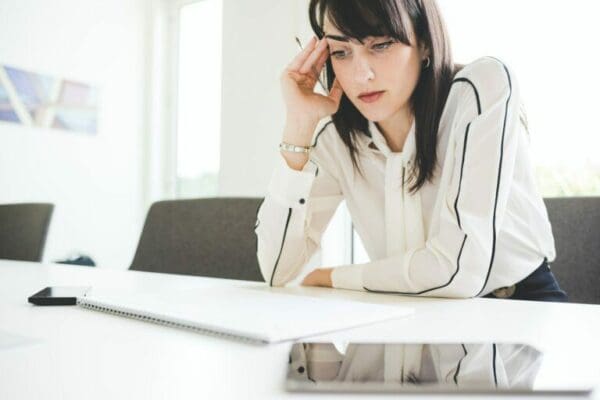 Stressed young ISFP businesswoman at office desk with notepad