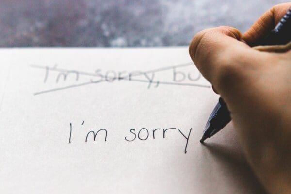 I'm sorry note getting written by a hand with a black ink pen