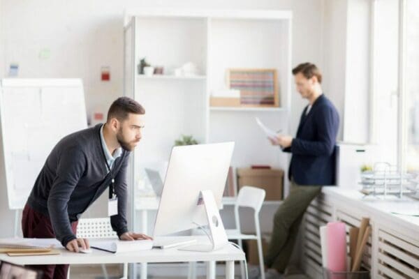 Two ISTP businessmen in office looking at computer and papers