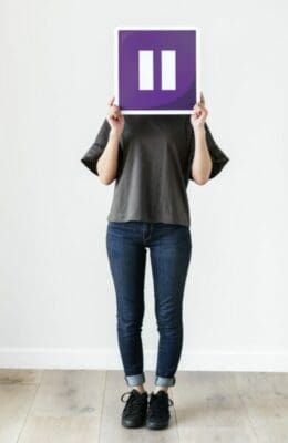 Girl holding a purple pause icon sign to hide her face