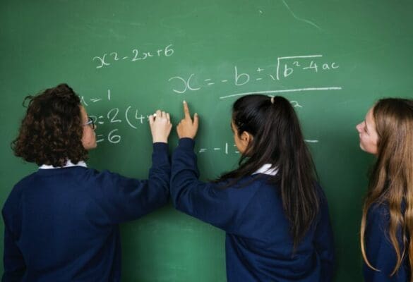 Female ISTP students solving a math problem on a chalkboard