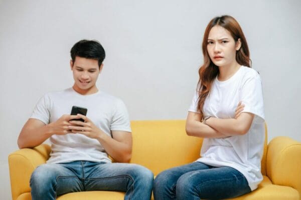 Man ignoring girl whilst on his phone reading text message and girl looking annoyed