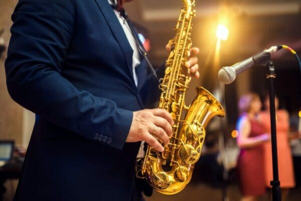 Shiny gold saxophone in the hand of musician in a blue suit on stage