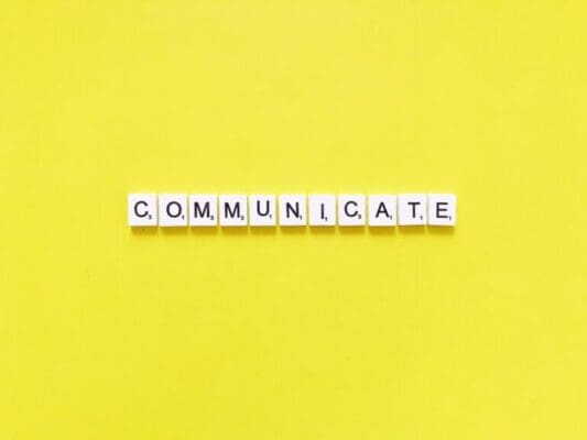 Communicate spelled with white cubes on yellow background