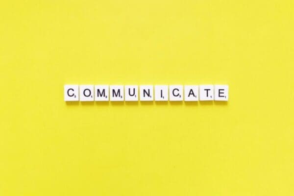 Communicate spelt with white word scramble cubes on yellow background