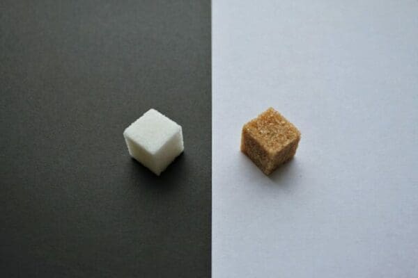 White and brown sugar cubes on opposite white and black surfaces 