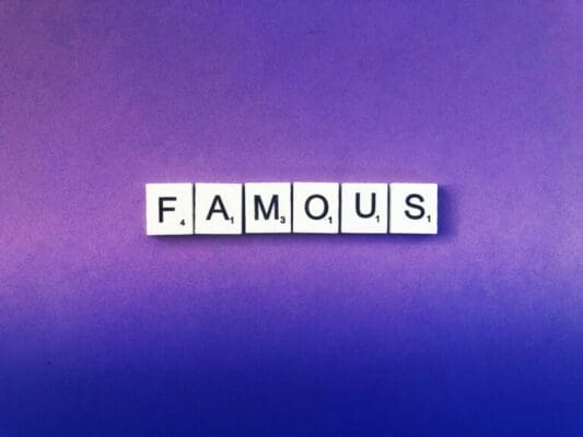 Famous spelled with white word scramble cubes on purple background