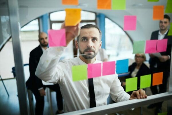 Male coworker using colourful post-it notes to Prioritise