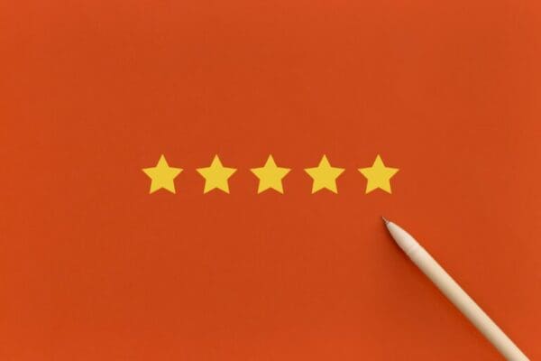Pen pointing to five 5 stars on orange background