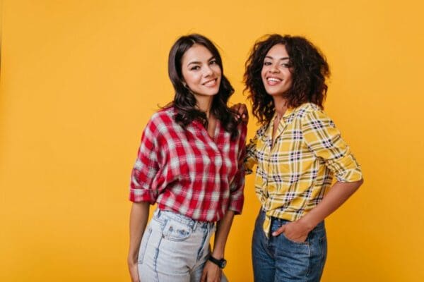 Two ISTJ and INTJ women in similar plaid shirts and jeans with orange background