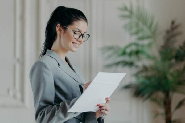 female ESTP lawyer dressed in a grey suit and glasses while writing on a paper