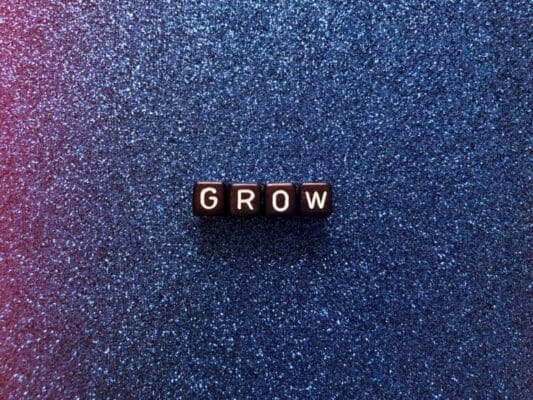 Grow spelled with black cubes on blue sparkly background