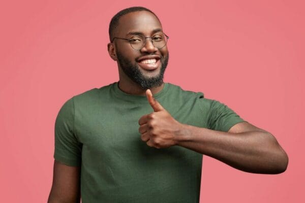 Man giving thumbs up for positive body language and pink background