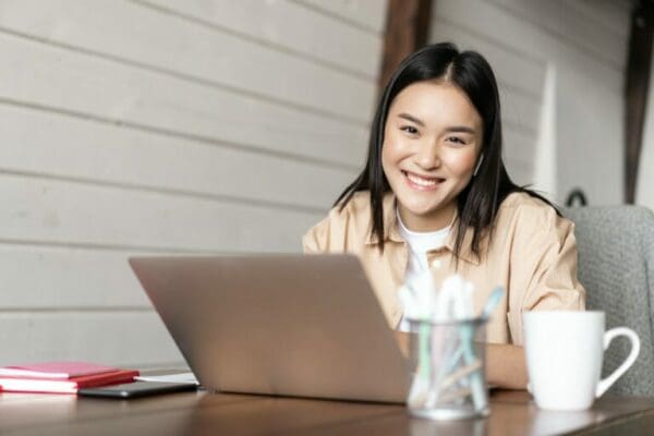 Smiling Korean girl working from home while researching how to work from home on her laptop