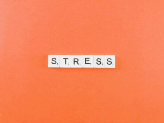 stress spelled with white word scramble tiles on peach background