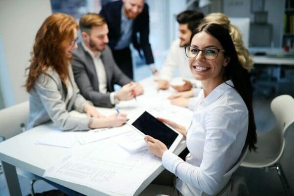Happy female worker smiling at the camera during a meeting with coworkers