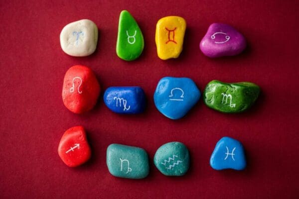 Top view of colorful stones with zodiac sun signs on red surface