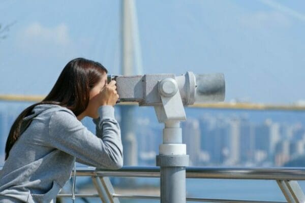 Strategic leader looking through a binocular to see in front of her