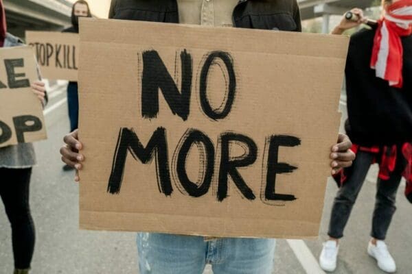 Protestor holding a cardboard sign with No More