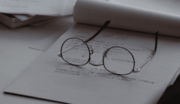 draft report writing structure on a notepad with a glasses