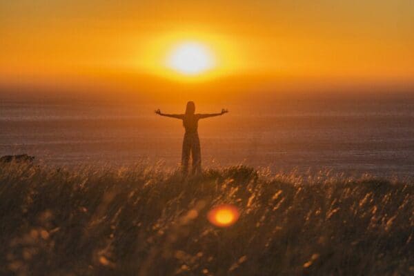 Person with arms stretched out with yellow sunset