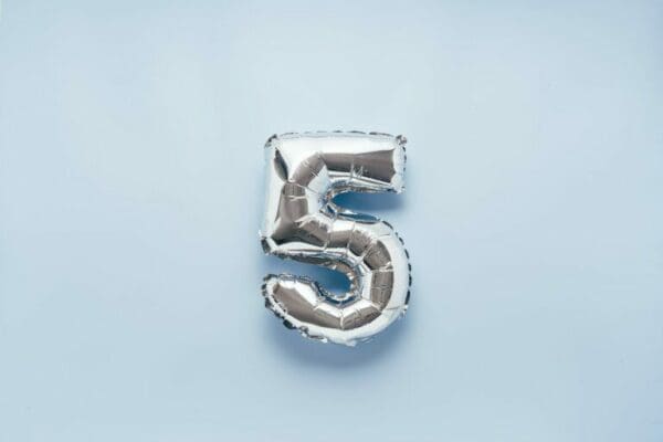 Silver number five balloon on light blue background