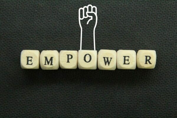 the word empower on a wooden cube with hands up