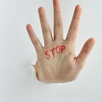 Hand with red text stop written on the palm showing a stop gesture