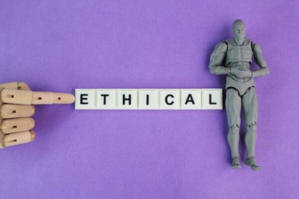 Ethical spelled with white cubes with robot hand pointing to it next to toy