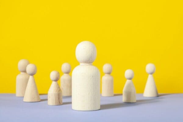 Line manager wooden figure on yellow background with employees behind