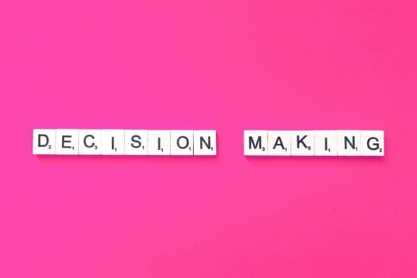 Decision making spelled with white tiles on pink background