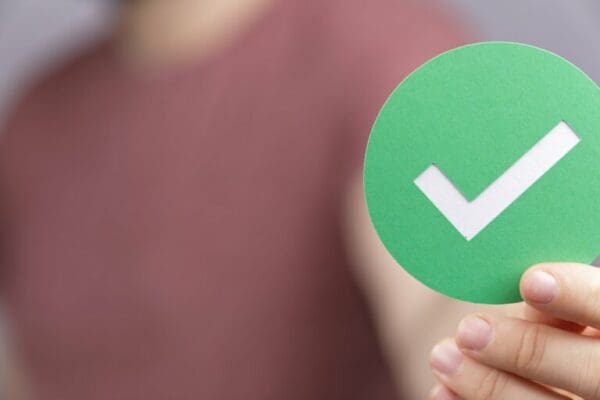 Man holding a green sign with a tick representing correct in the 7cs of communication