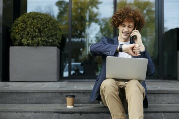 young businessman talking on cellphone while checking time