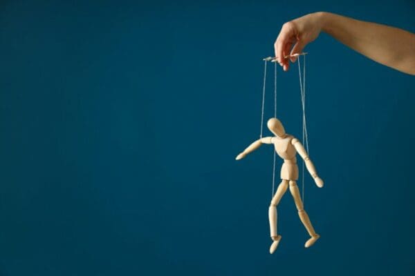 Hand controlling a wooden doll by strings for 7 Cs of communication