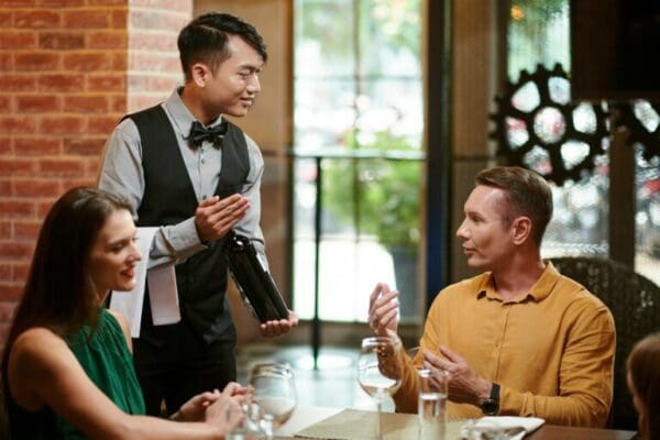 Waiter asking guests around table in restaurant is everything okay?