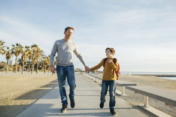 Father and son walking on beach promenade for life lessons