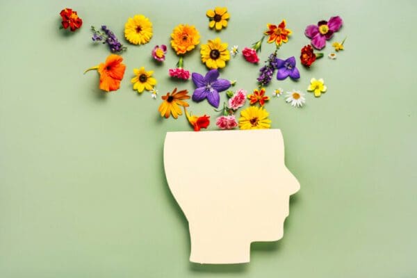 Human head cutout with flowers coming from the top representing Mental health