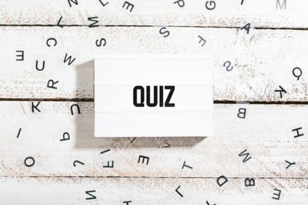 Quiz word on white box with scrambled letters on wooden table