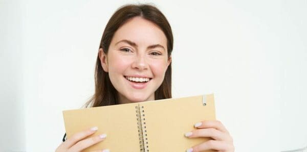 Top view of happy woman smiling while showing the back of her daily planner