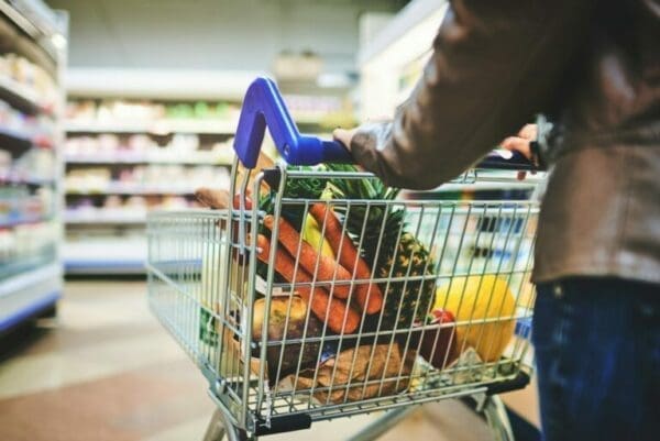 Woman pushing shopping trolley down supermarket isle