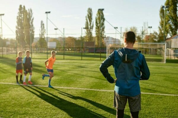 Soccer coach training kids practicing on grass field