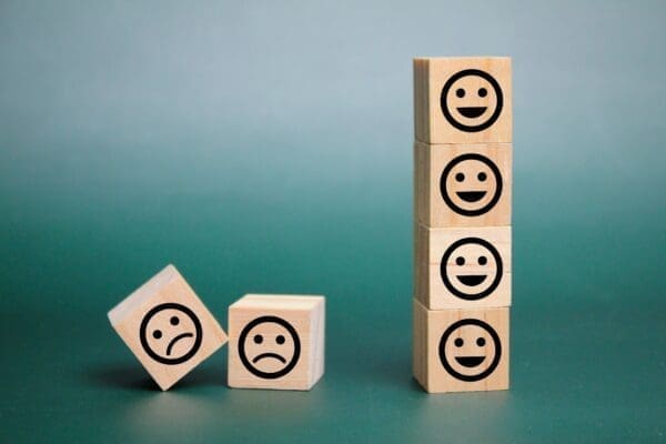 wooden cubes arranged with smiley and two angry emoticon icons